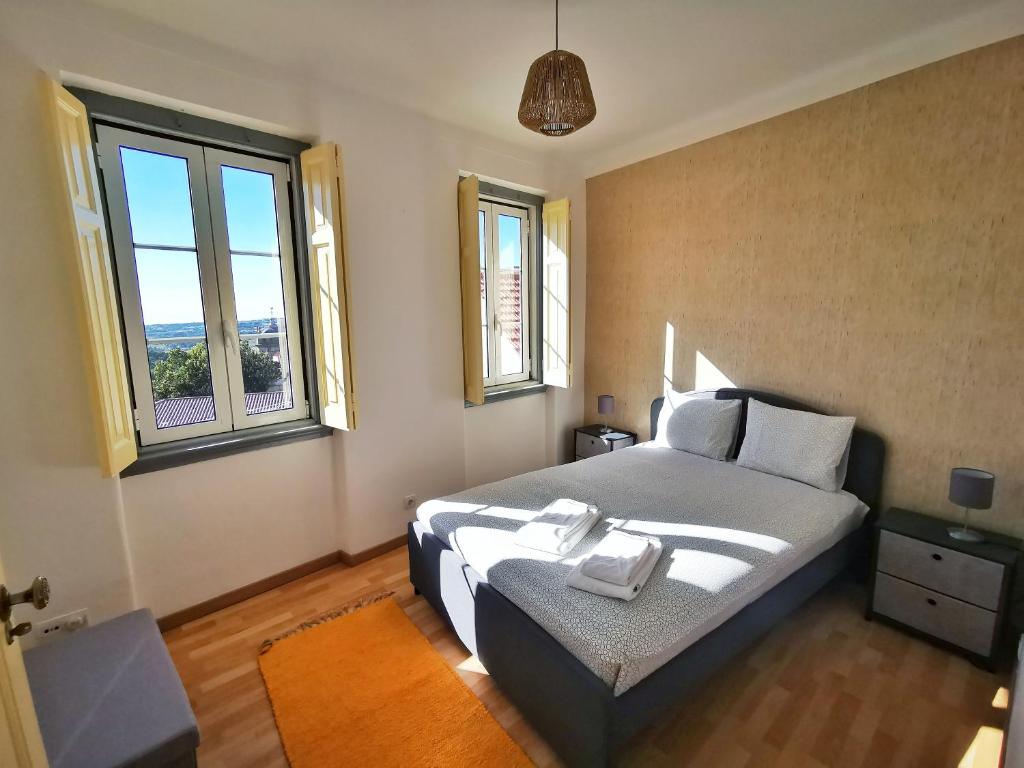 a bedroom with a bed and two windows at Casa da Ferraria in Sintra