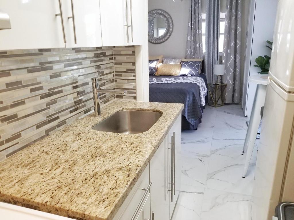 a kitchen with a sink and a room with a bed at Glam Private Studio 4 Miles from Beach in Hollywood