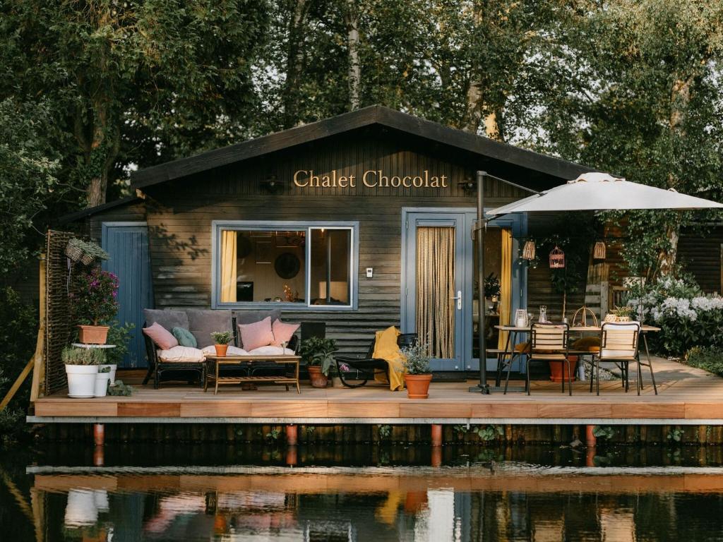 Cabaña pequeña con mesa, sillas y sombrilla en Chalet in Geel in quiet location by the water, en Geel