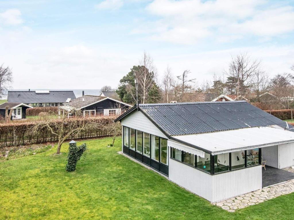 ein weißes Haus mit schwarzem Dach auf einem grünen Feld in der Unterkunft 6 person holiday home in Nordborg in Nordborg