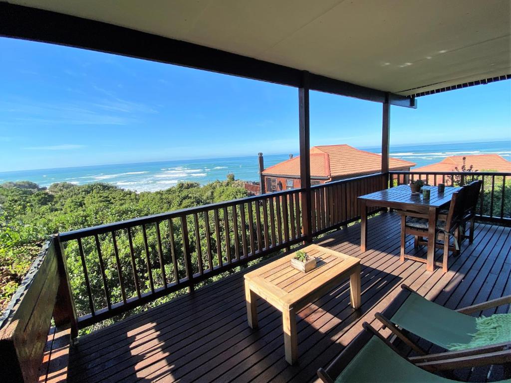 uma varanda com uma mesa e cadeiras e o oceano em Tiptol Couple's Retreat em Jeffreys Bay