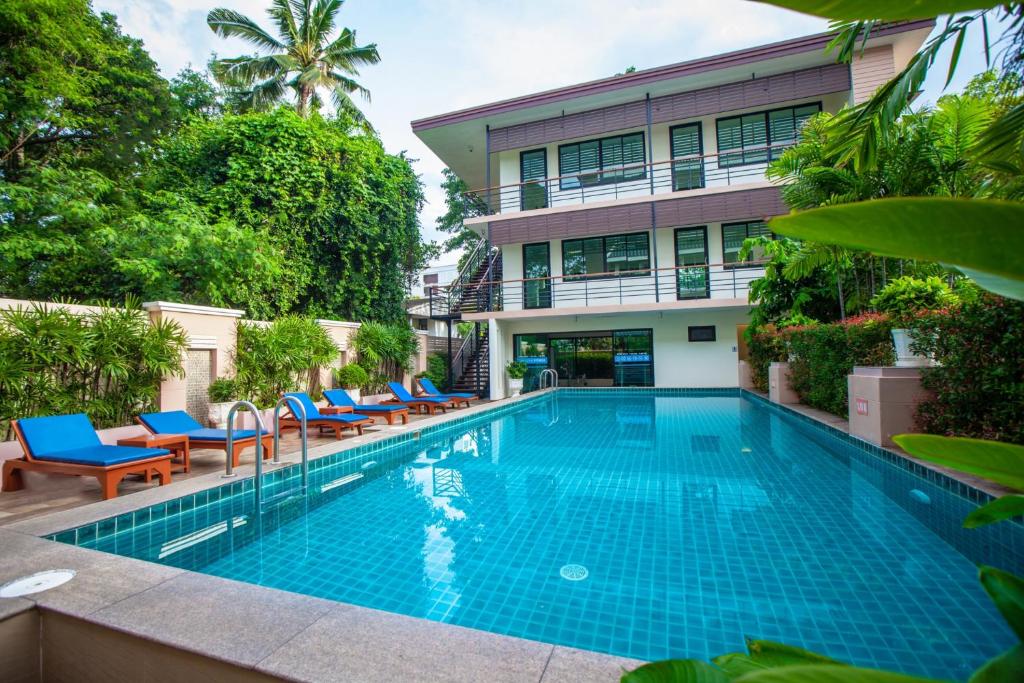 A bright garden pool is enclosed by tropical planting and a low-rise building.