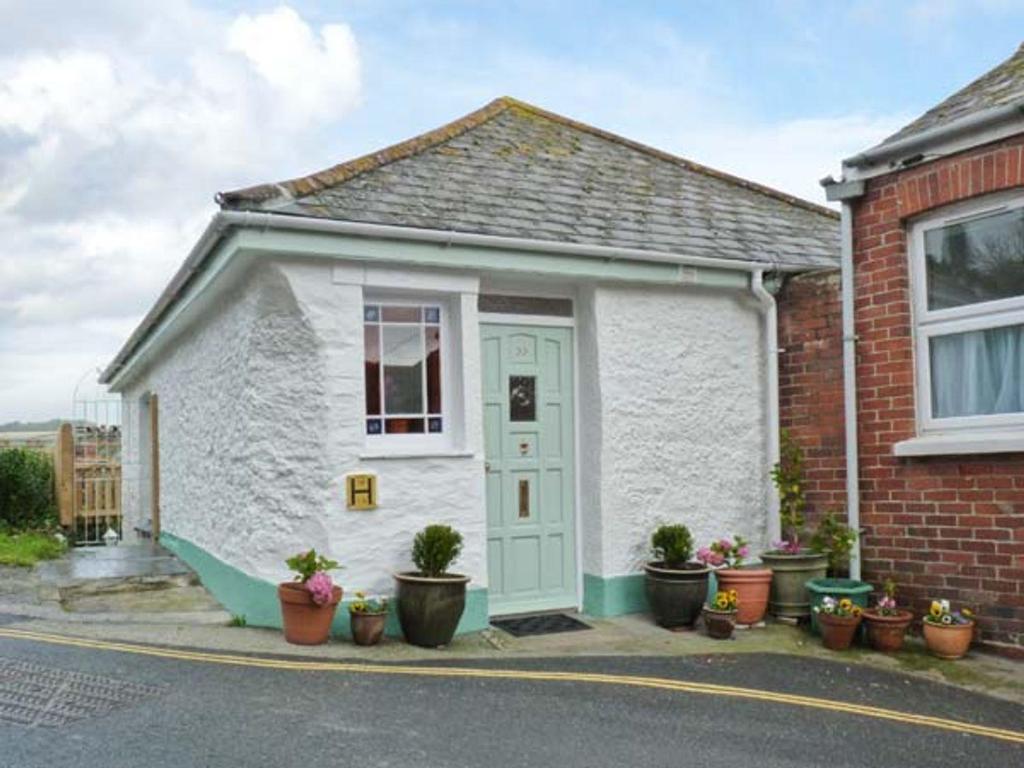 a small house with a green door and potted plants at Rose Cottage in St Austell