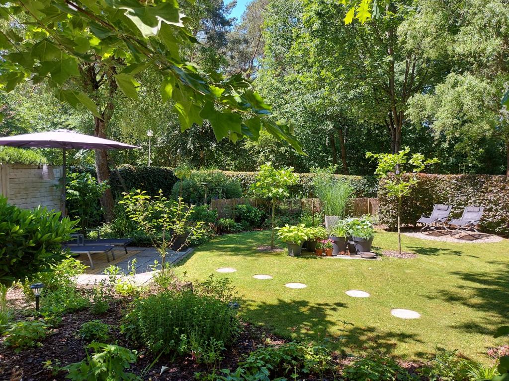 un jardin avec une pelouse, des chaises et un parasol dans l'établissement Vakantiehuis E62 Rekem Limburg, à Lanaken