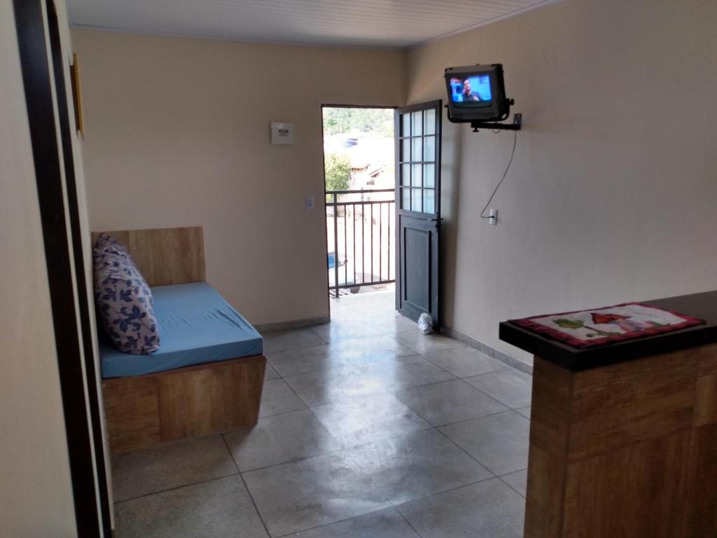 uma sala de estar com um sofá e uma televisão na parede em LOCANDA DA SERRA - Aptos Mobiliados e Suítes por Temporada em Barra do Garças