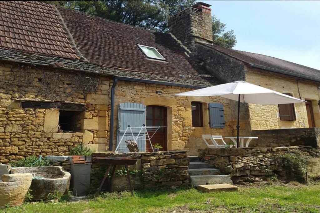 a stone house with an umbrella and a table at L'abreuvoir, Gite du 18 siecle, accés indépendant in Carsac-Aillac