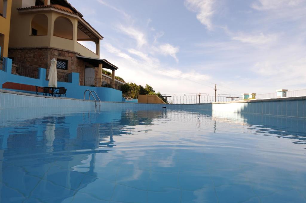 a swimming pool with blue water in front of a building at Vallemare Residence e Studios in Baja Sardinia