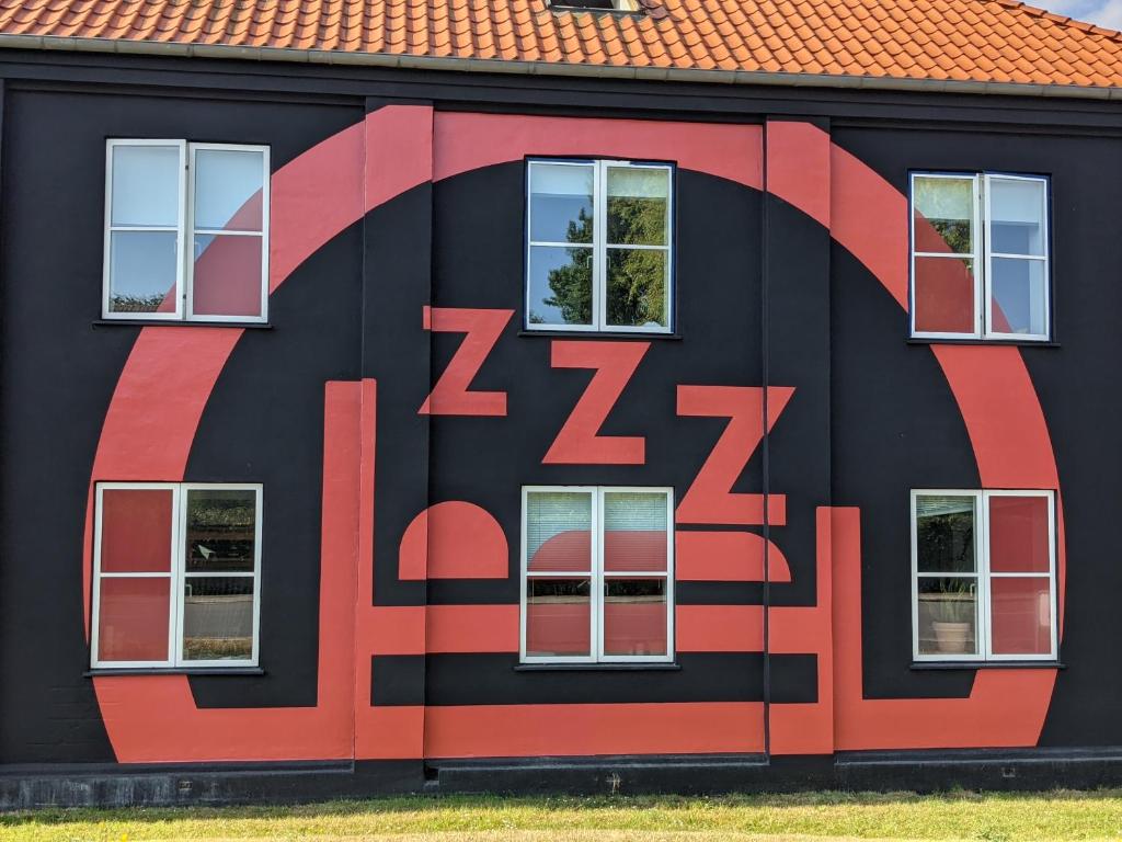 a red brick building with a mural on the side of it at Nexø Modern Hostel. Private Rooms in Neksø
