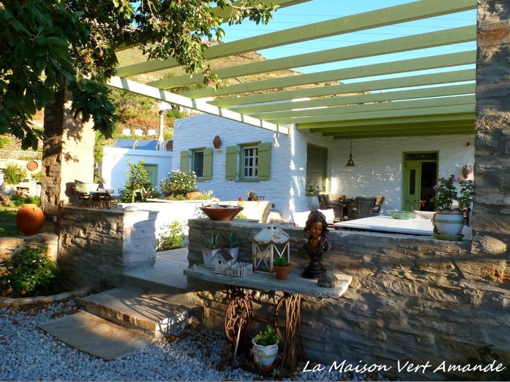 a stone patio with a pergola and a house at La Maison Vert Amande in Spathi 