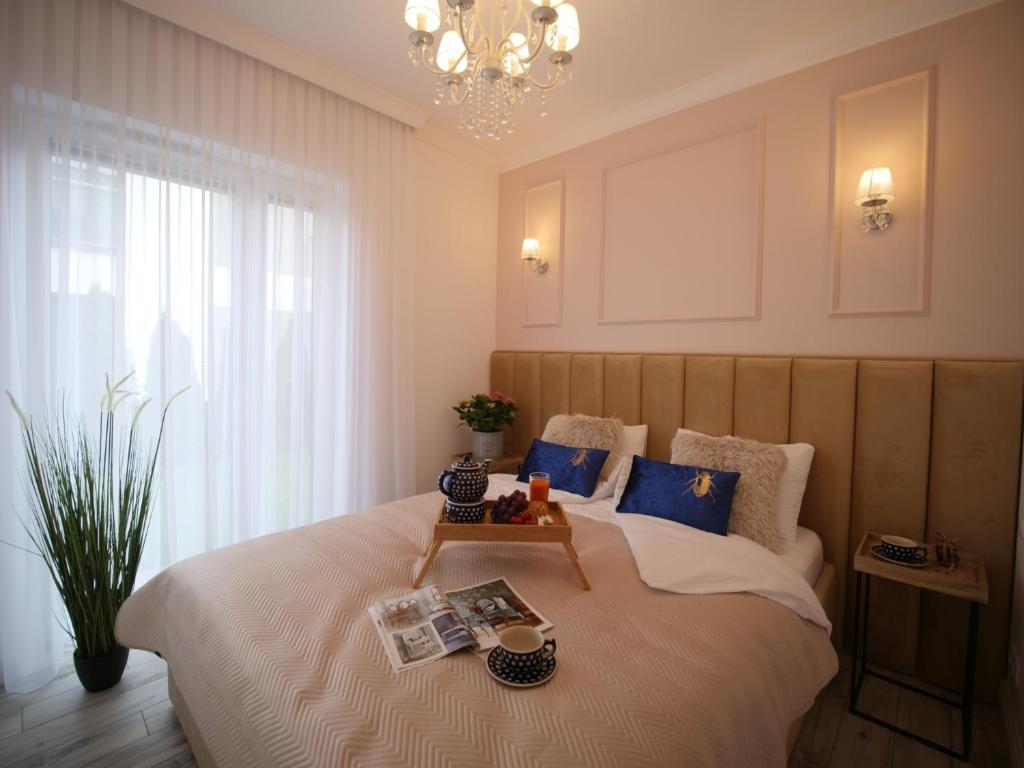 um quarto com uma cama grande e um lustre em Luksusowe Apartamenty Bursztynowy Las ,,Leśny Poranek'' z ogrodem i widokiem na las Ustka em Ustka