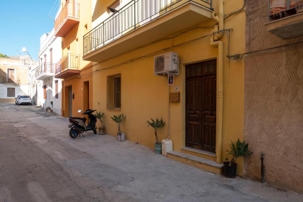 un scooter garé devant un bâtiment jaune dans l'établissement Appartamento nel centro storico di Sciacca, à Sciacca