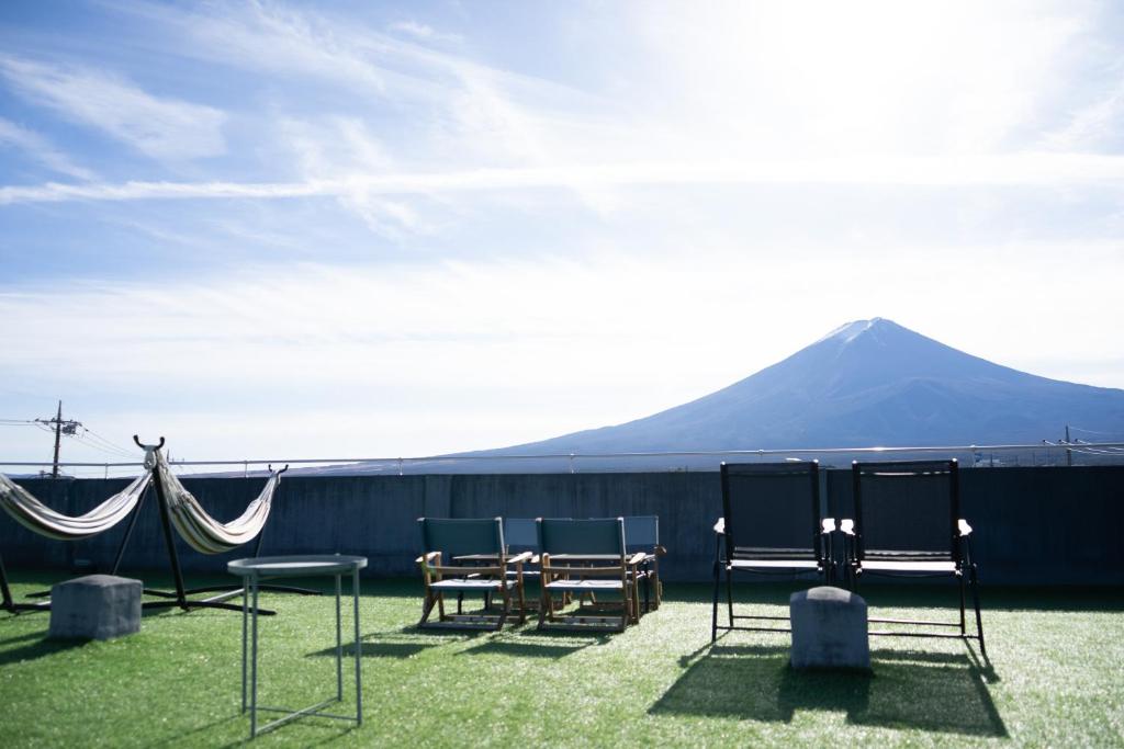 un groupe de chaises et de tables avec une montagne en arrière-plan dans l'établissement Fuji Guest House Ao, à Fujikawaguchiko