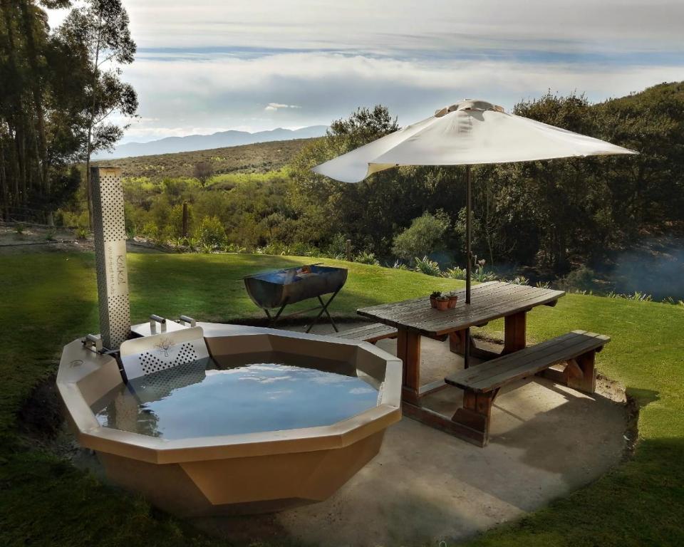 uma banheira de hidromassagem com uma mesa de piquenique e um guarda-sol em Treyntjes Rivier Cottages em Caledon