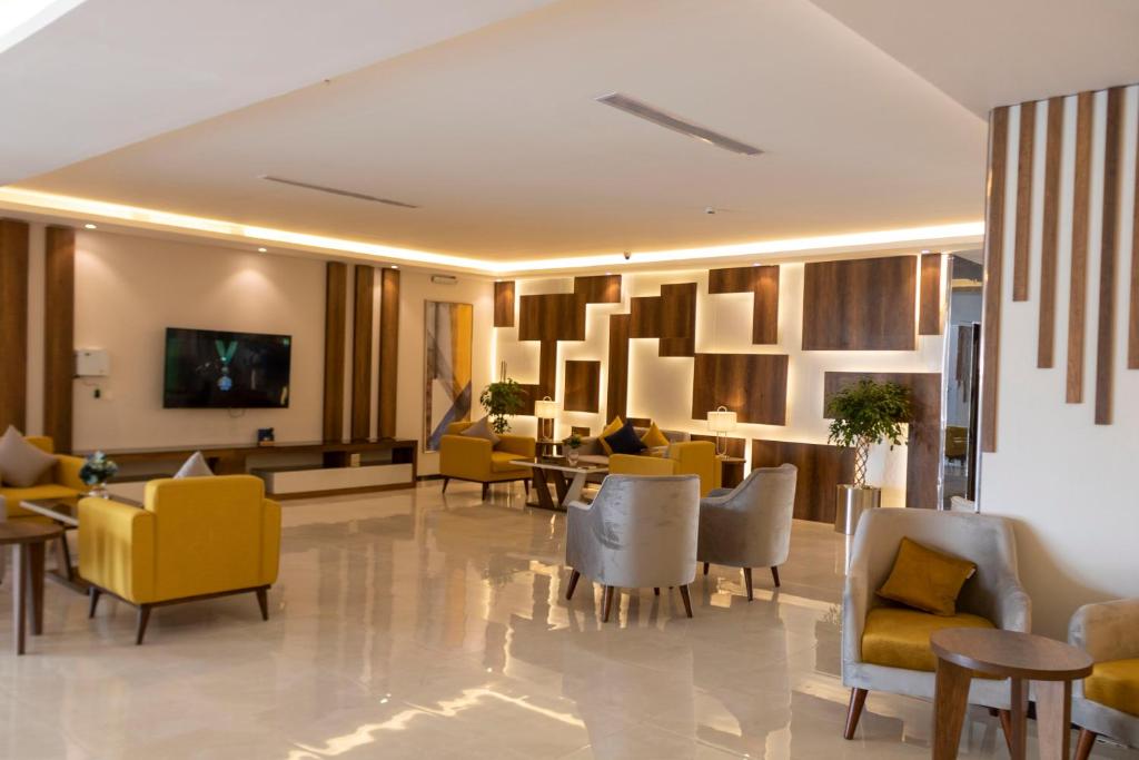 un hall d'accueil avec des chaises et des tables jaunes dans l'établissement The Palace Hotel Suites, à Khamis Mushait
