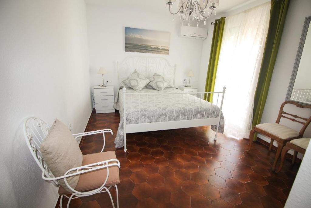 a bedroom with a bed and chairs and a chandelier at Pueblo Andaluz 670 in Torrox Costa