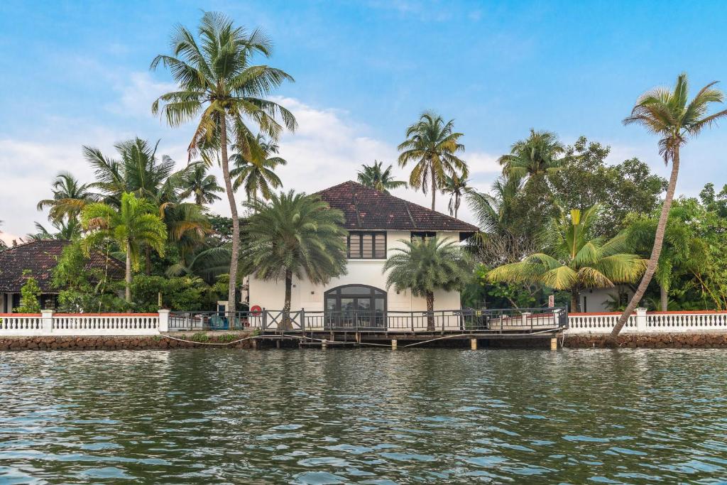 ein Haus am Wasser mit Palmen in der Unterkunft Club Mahindra Cherai Beach in Cherai Beach