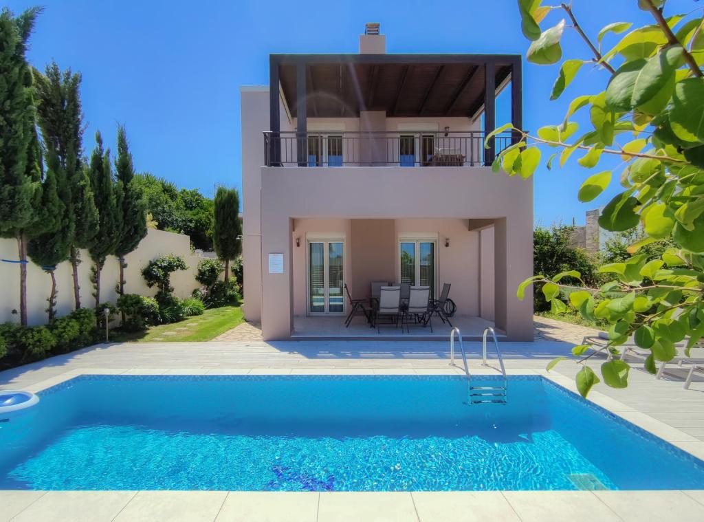 a villa with a swimming pool in front of a house at Aphrodite in Adelianos Kampos