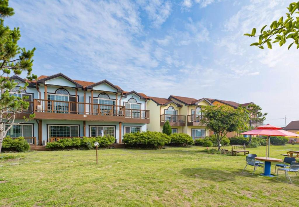 a large house with a yard with a table and chairs at Jeju Time-Travel Pension in Jeju