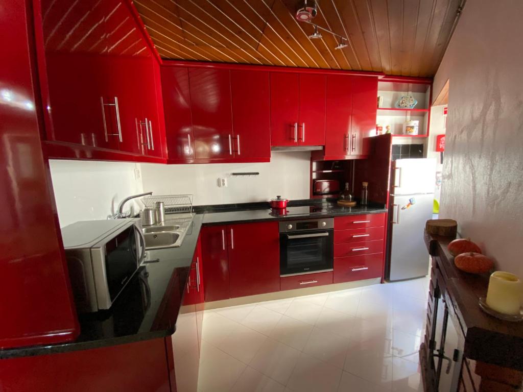 a kitchen with red cabinets and a white refrigerator at Casa do Pelourinho in Coja