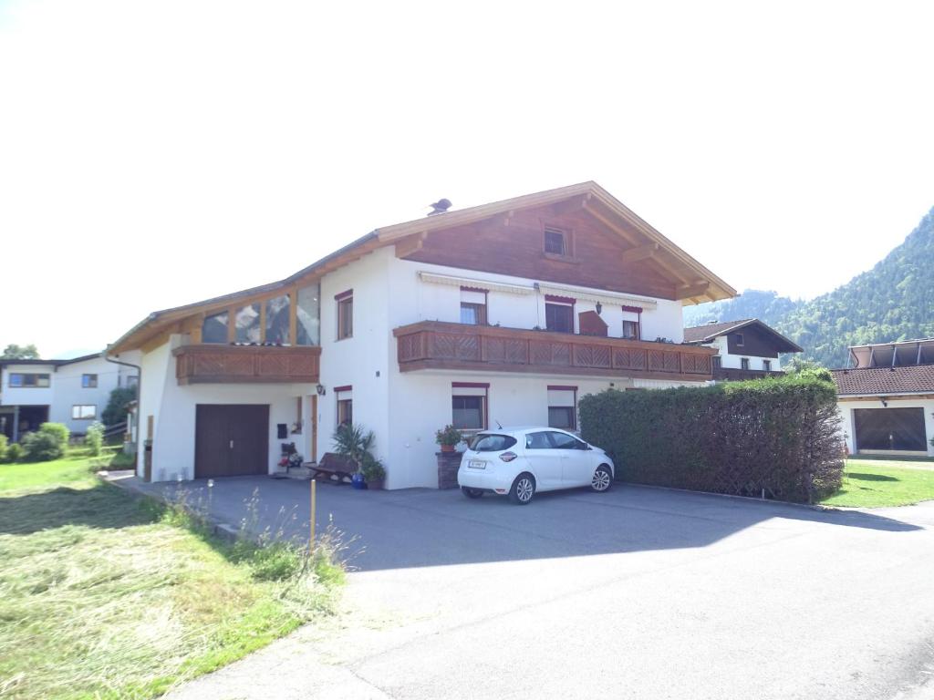 una casa blanca con un coche aparcado en una entrada en Tiefenbrunn en Ehenbichl