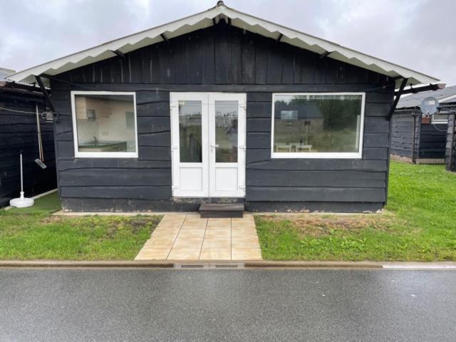a black house with a white door in a yard at Camping Thalassa Belgische Kust Chalet in Bredene