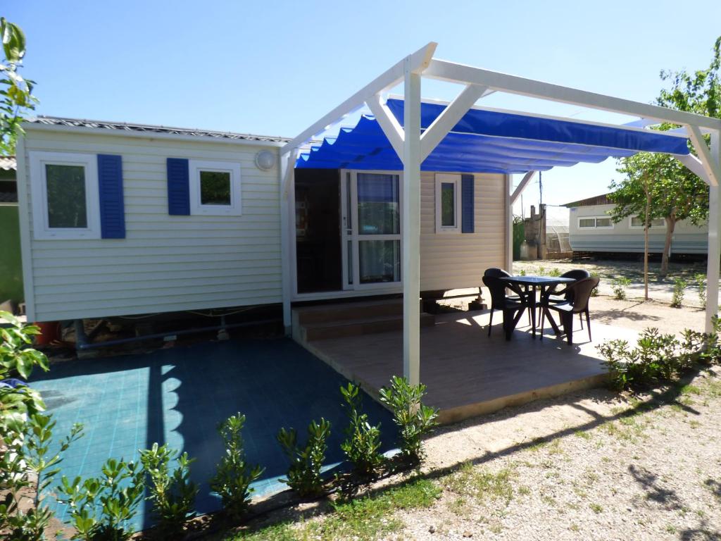 a patio with a table and a blue awning at Camping Barraquetes in Sueca