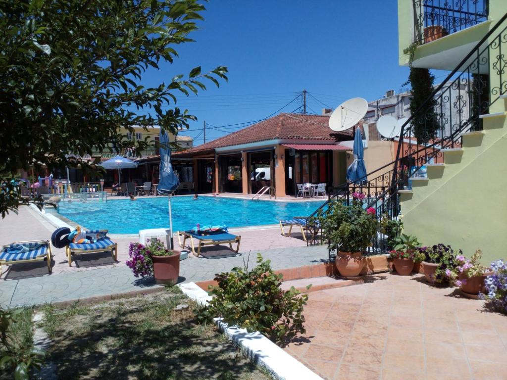 a swimming pool with chairs and a building at Amadeus Hawaii Apartments & Studios in Sidari