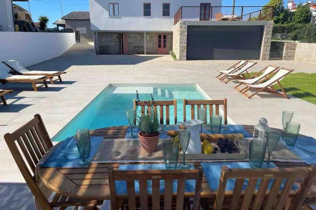 uma mesa com cadeiras ao lado de uma piscina em Porto-Braga Family Country House (Private Pool) em Ferreiró
