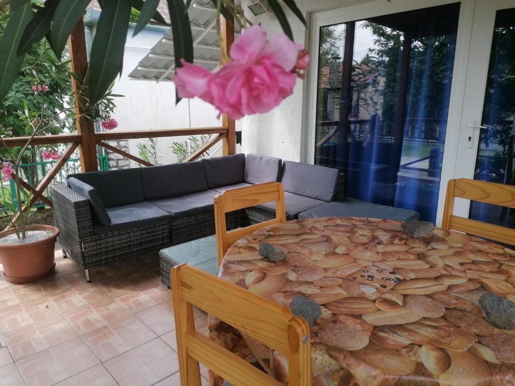 eine Terrasse mit einem Tisch, Stühlen und einer rosa Blume in der Unterkunft Aleksandros in Mezőkövesd