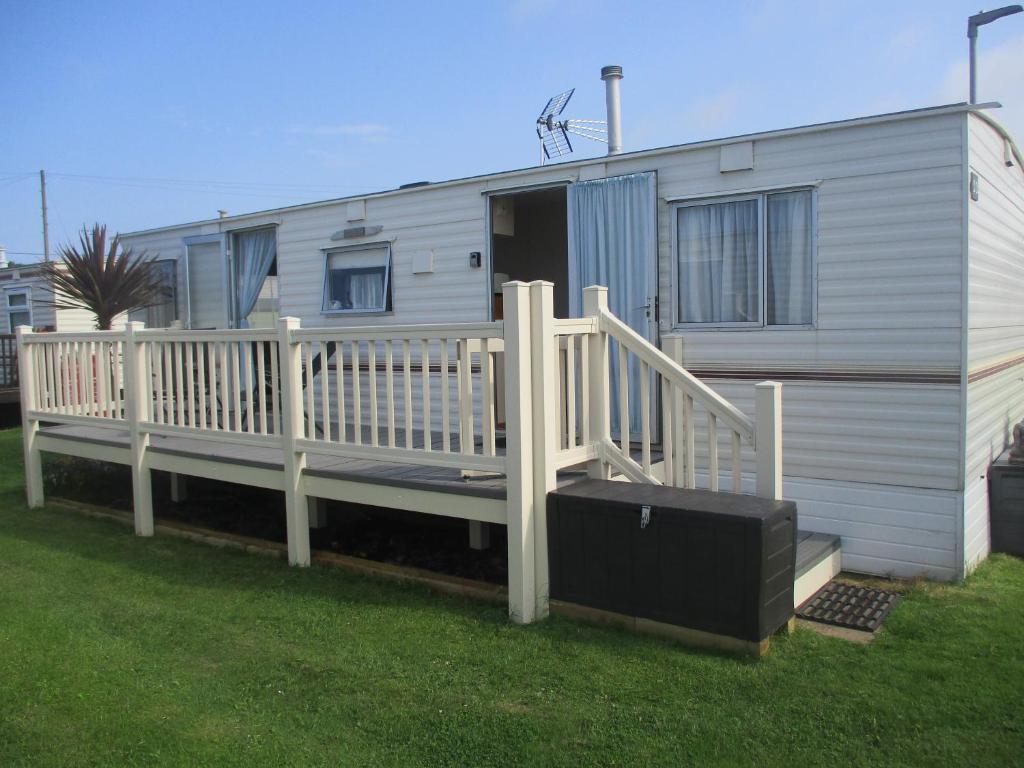 a mobile home with a porch and a deck at Summer Breeze Caravan in Bacton