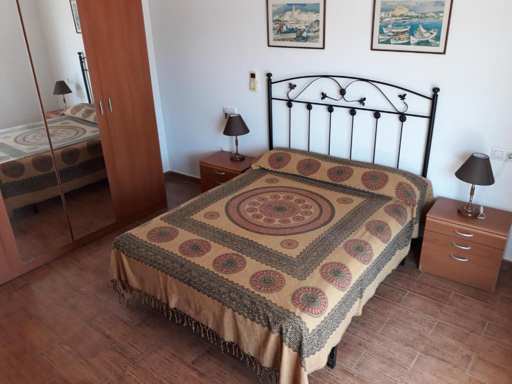 een slaapkamer met een bed, 2 lampen en een spiegel bij Casa Angelus in Águilas