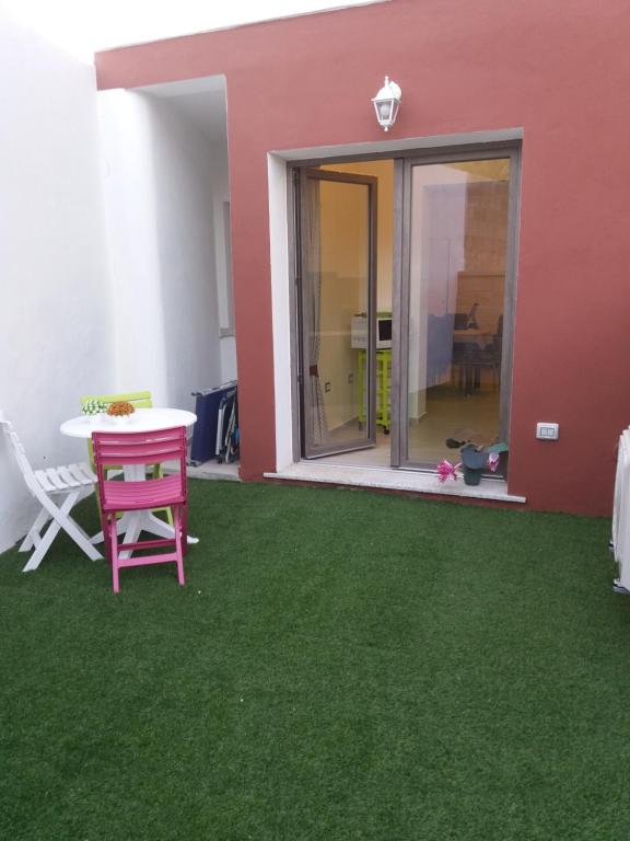 een patio met groen gras en een tafel en een gebouw bij Casa Giada in SantʼAntìoco