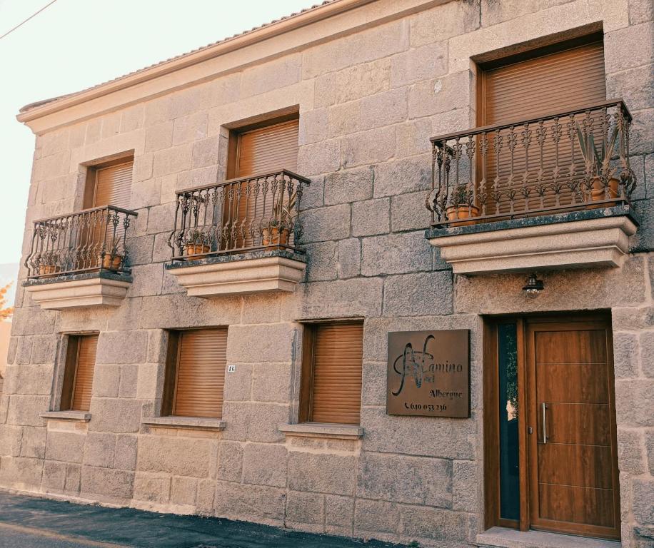 - un bâtiment en pierre avec un balcon et un panneau sur celui-ci dans l'établissement Albergue Hostel Nuestra Señora del Camino, à Combarro