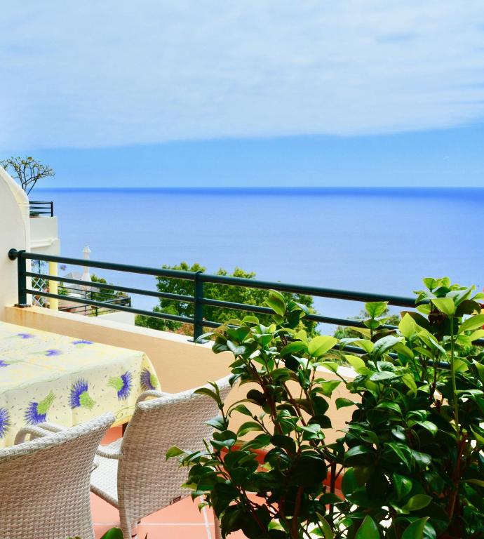 a table and chairs and a plant on a balcony at Jardim do Arco "Esmee" in Arco da Calheta