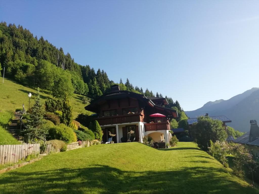 uma casa numa colina com um relvado verde em Chambres en chalet petit déjeuner inclus em La Côte dʼArbroz