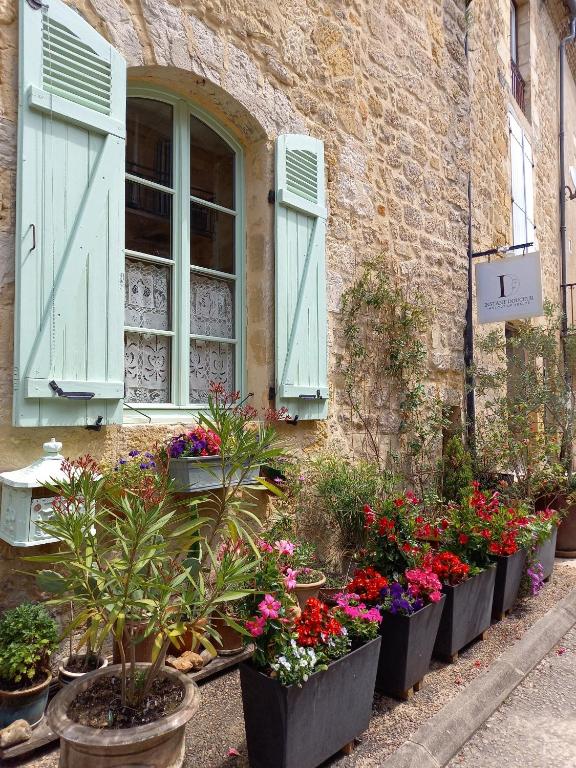 a bunch of flowers in pots in front of a building at chambre d hôtes les remparts in Saint-Cyprien