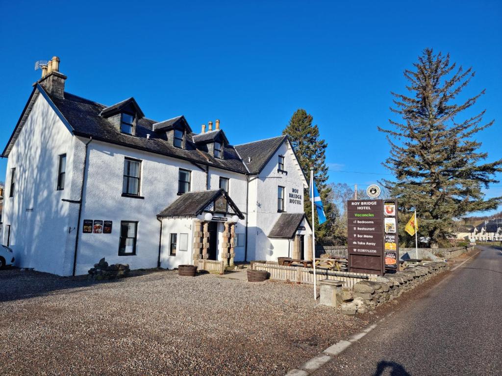 une maison blanche avec un panneau devant elle dans l'établissement Roy Bridge Hotel, à Fort William