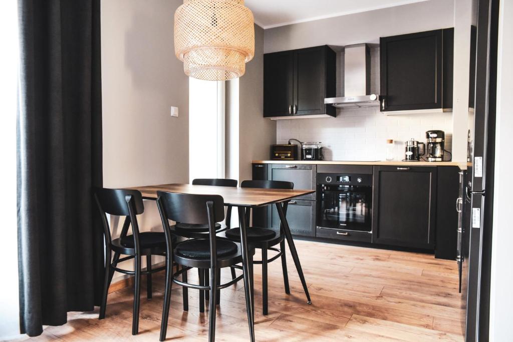 een keuken met zwarte kasten en een houten tafel en stoelen bij Flat 10 in Szczecin