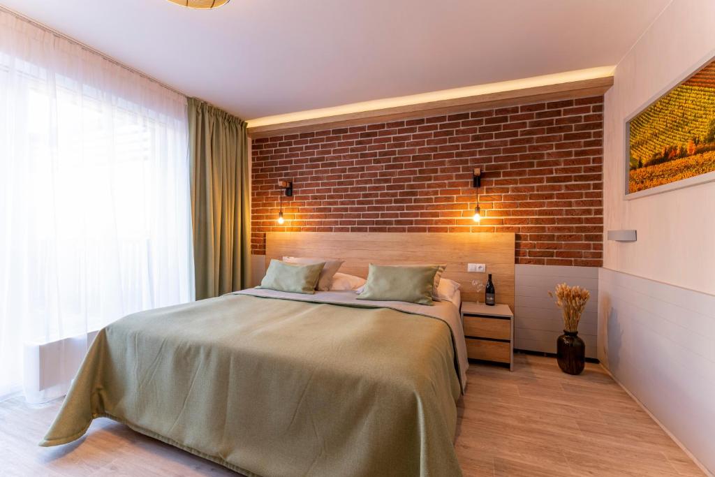 1 dormitorio con 1 cama grande y pared de ladrillo en Hotel Aqualand Inn en Pasohlávky