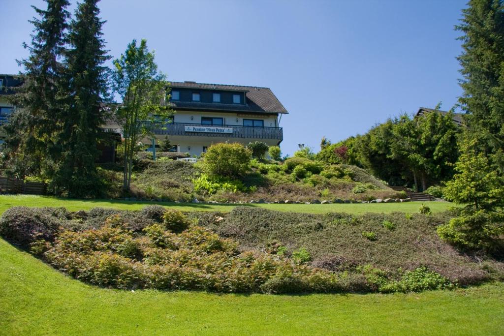 uma casa no topo de uma colina com um jardim em Pension Haus Petra em Altenau