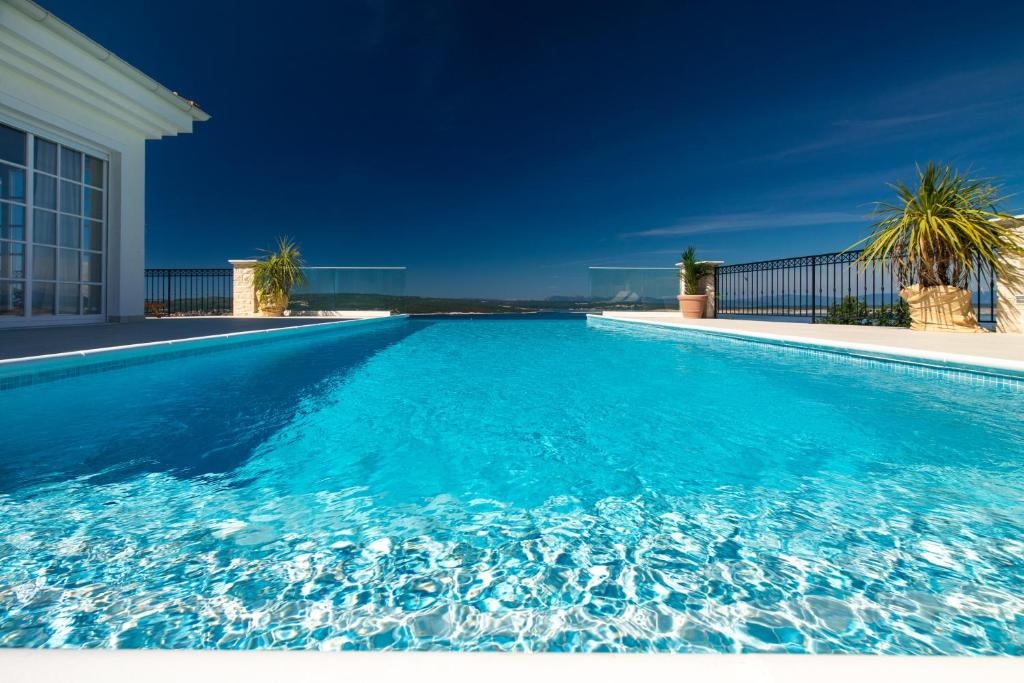 uma grande piscina com água azul em Villa VESPERA-Infinity heated pool em Crikvenica