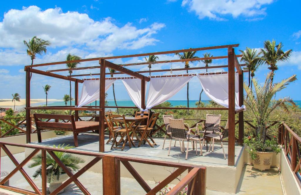 a deck with a table and chairs on the beach at Pousada Villa Flores in Jericoacoara