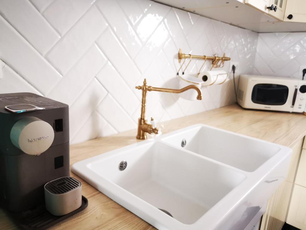 a white sink in a kitchen with a microwave at Veled Teljes Vendégház Badacsony in Badacsonytomaj