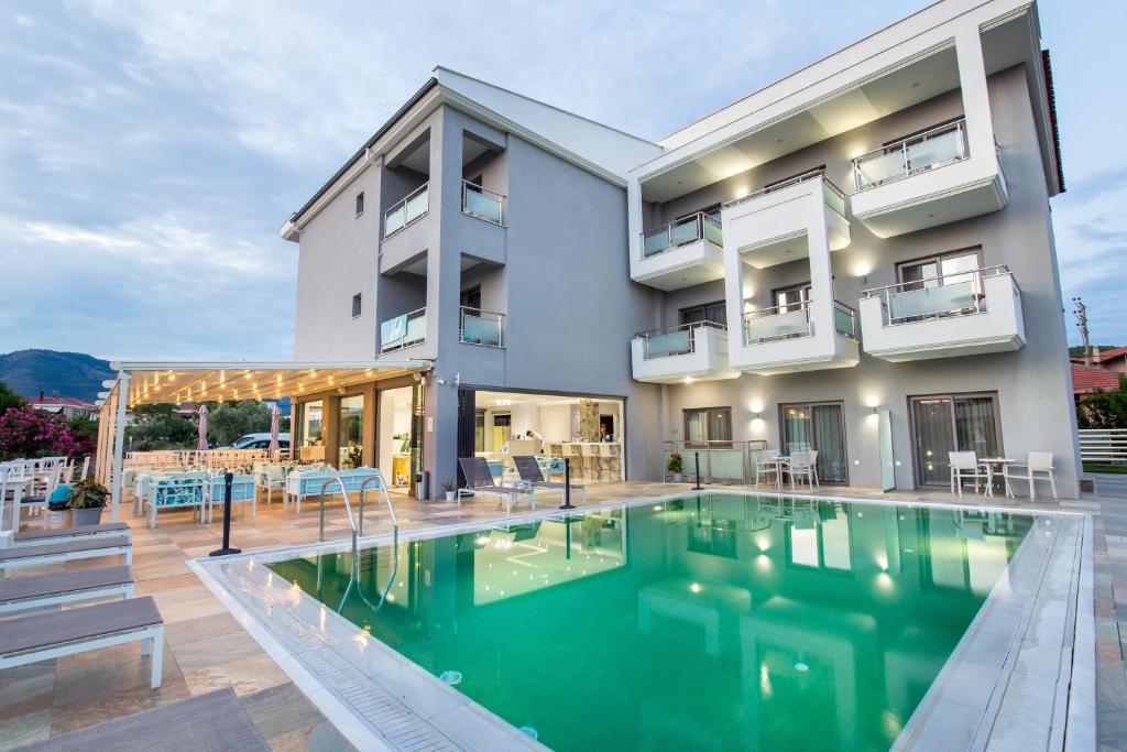 a house with a swimming pool in front of a building at Patiras Deluxe B&B in Limenaria