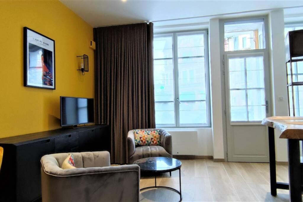 - un salon avec deux chaises et une télévision dans l'établissement Appartement T2 Centre-ville Entièrement rénové, à Reims