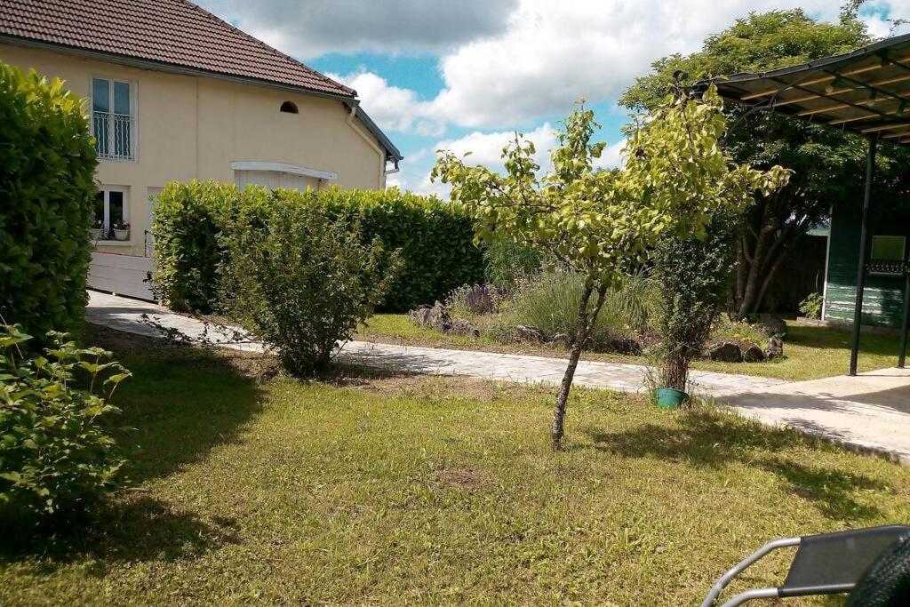 a small tree in a yard next to a house at Les Moineaux Jura in Chavéria