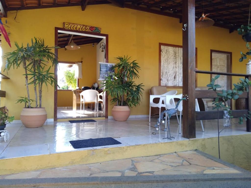 a restaurant with a yellow wall with chairs and plants at Pousada Licuri in Serra do Cipo