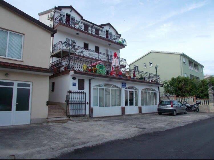 un edificio bianco con un'auto parcheggiata di fronte di Villa Pandza a Seget Vranjica