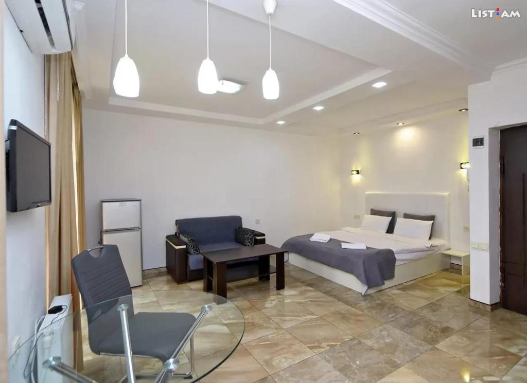 ein Schlafzimmer mit einem Bett, einem Stuhl und einem TV in der Unterkunft Apartaments on Komitas 20 in Yerevan