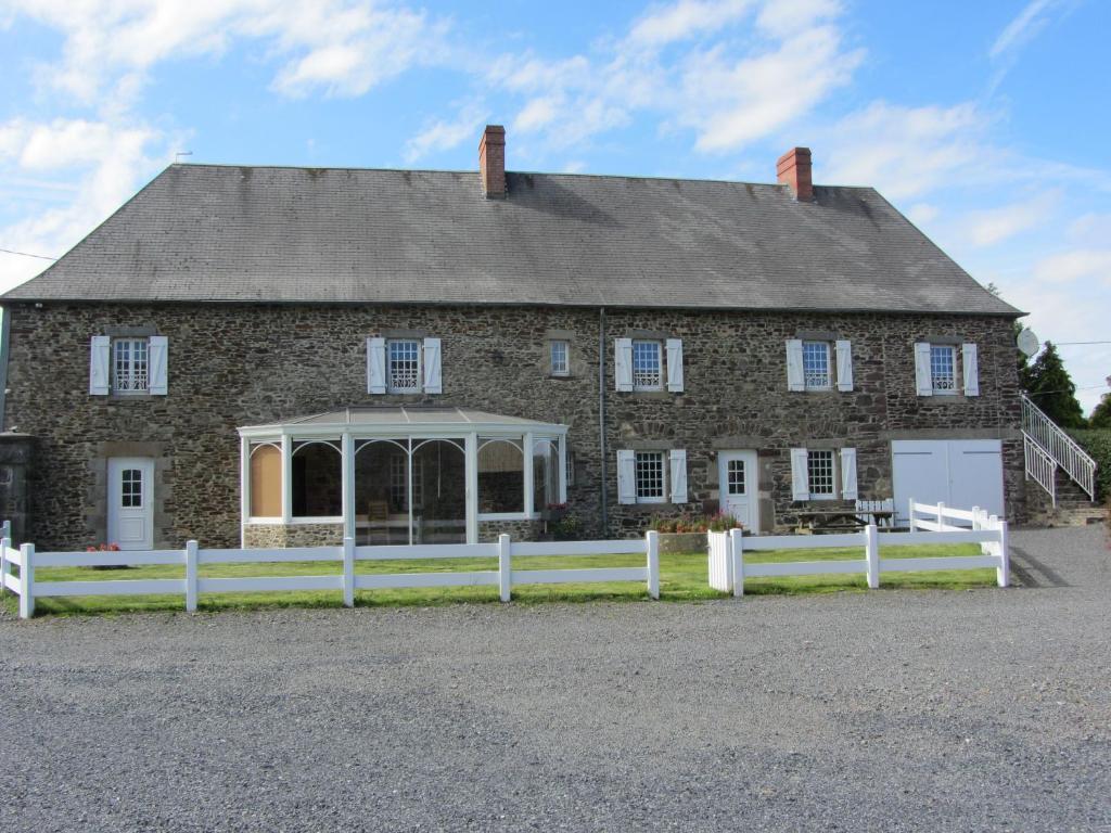 una gran casa de ladrillo con una valla blanca en La Robinière, en Cerisy-la-Salle